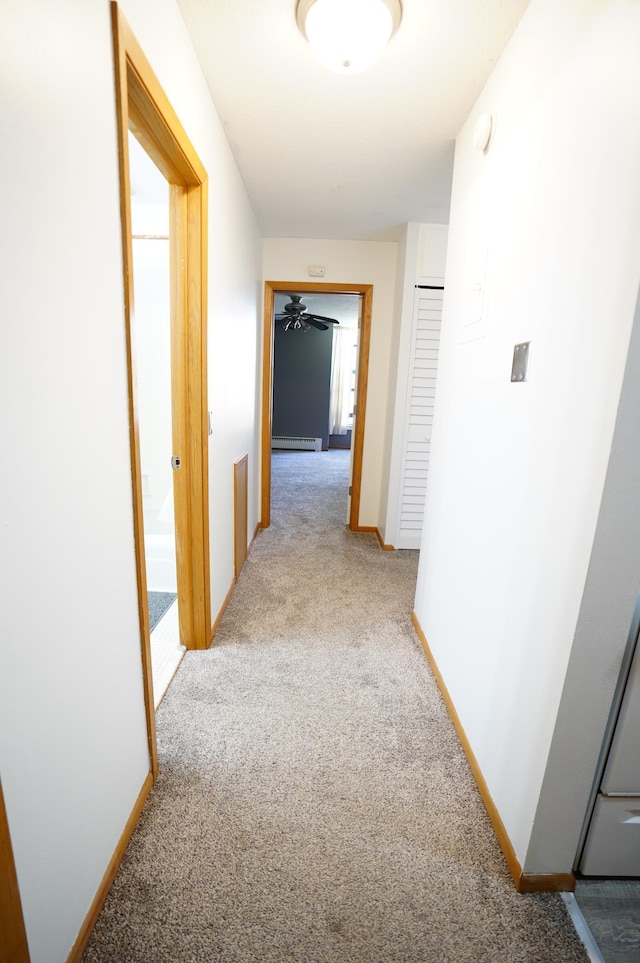 corridor with baseboards, a baseboard radiator, and light colored carpet