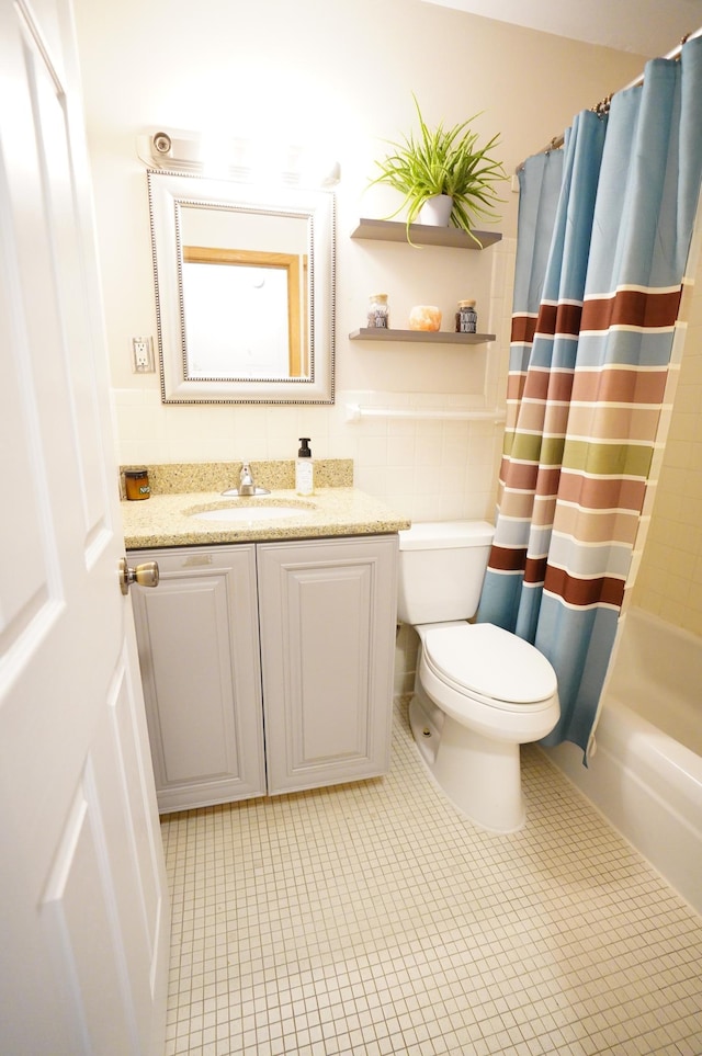 full bathroom featuring tile patterned flooring, vanity, toilet, shower / bath combo with shower curtain, and tile walls
