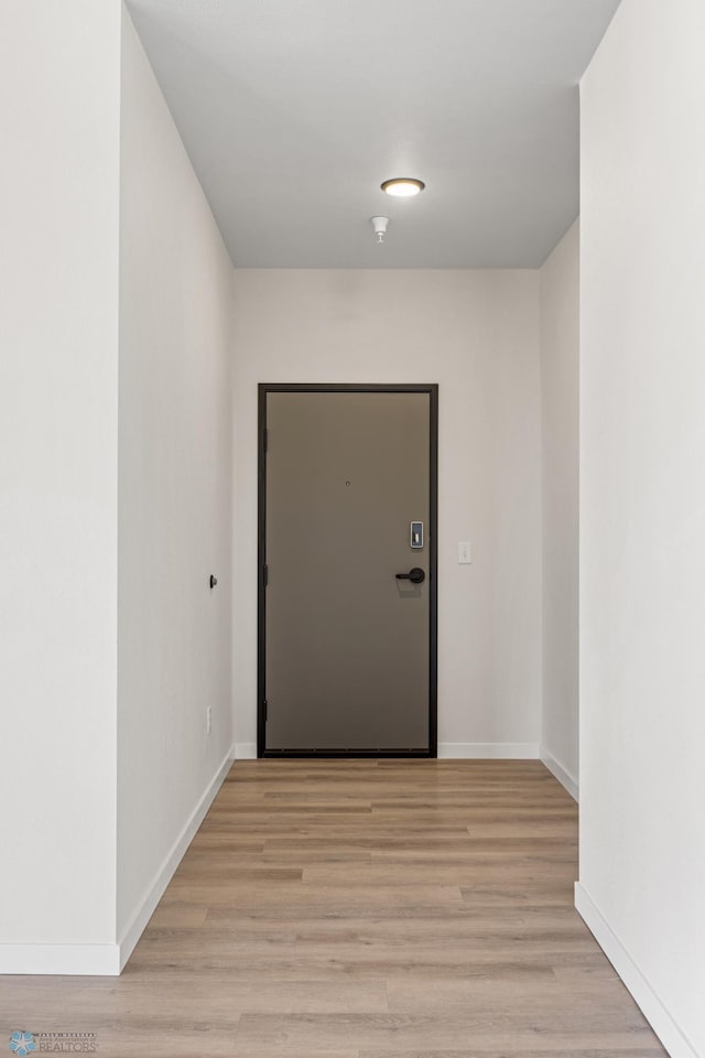 doorway featuring baseboards and light wood-style floors