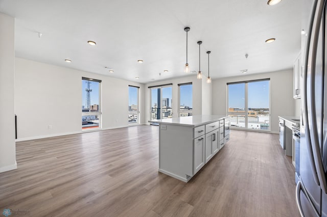 kitchen featuring light countertops, open floor plan, a kitchen island, and light wood-style floors