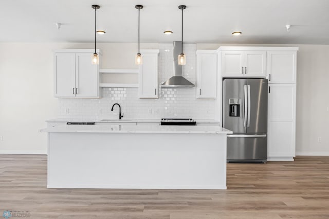 kitchen with wall chimney range hood, tasteful backsplash, a sink, stainless steel appliances, and white cabinetry