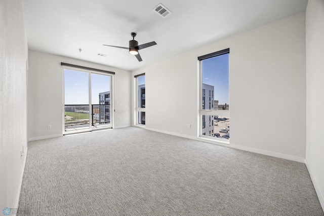 spare room with carpet floors, baseboards, ceiling fan, and visible vents
