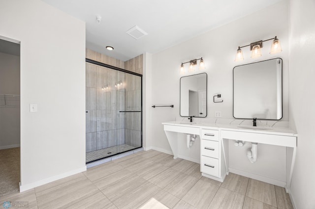 bathroom featuring baseboards, a sink, a tile shower, and double vanity
