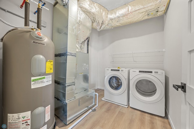 laundry room with laundry area, wood finished floors, baseboards, electric water heater, and independent washer and dryer