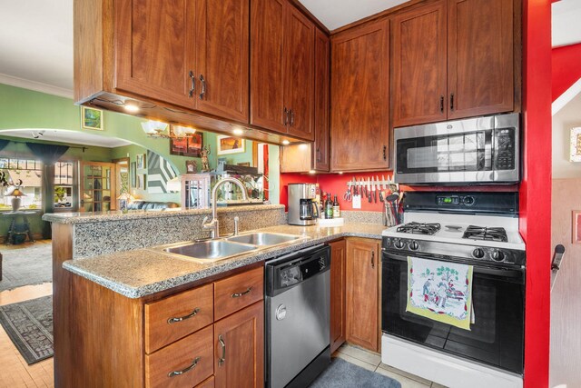 kitchen with a sink, a peninsula, ornamental molding, arched walkways, and appliances with stainless steel finishes