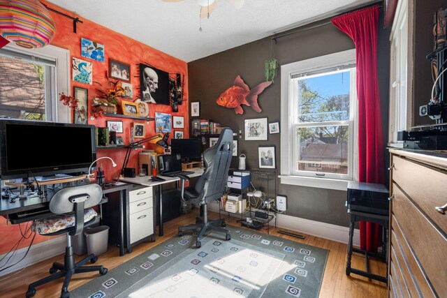 home office with plenty of natural light, wood finished floors, a ceiling fan, and baseboards