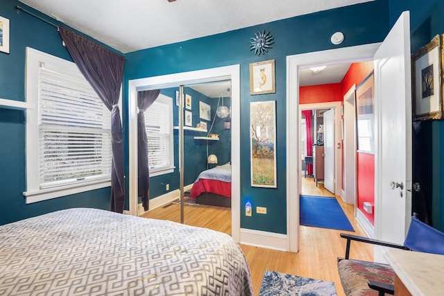 bedroom with a closet, wood finished floors, and baseboards