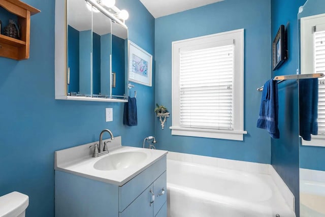 full bath with a garden tub, vanity, and toilet