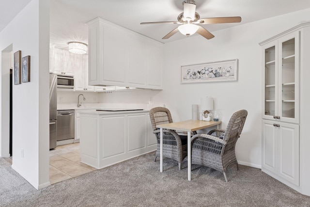 dining space featuring light colored carpet, a ceiling fan, and baseboards