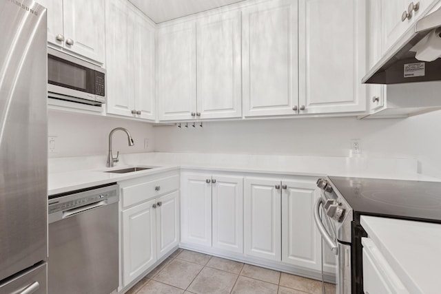 kitchen featuring white cabinetry, under cabinet range hood, a sink, appliances with stainless steel finishes, and light tile patterned floors
