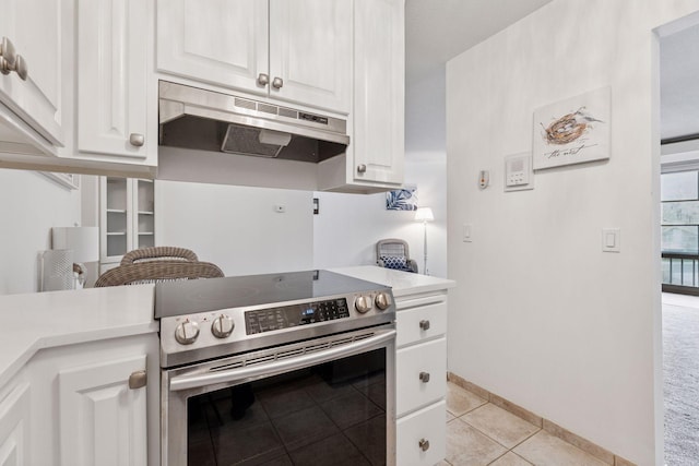 kitchen with stainless steel range with electric stovetop, light countertops, white cabinetry, light tile patterned floors, and under cabinet range hood