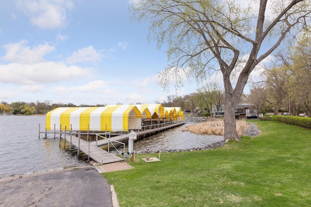 view of dock with boat lift, a water view, and a yard
