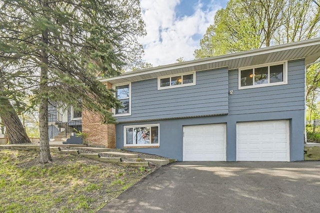 view of front of house featuring asphalt driveway, stucco siding, and an attached garage