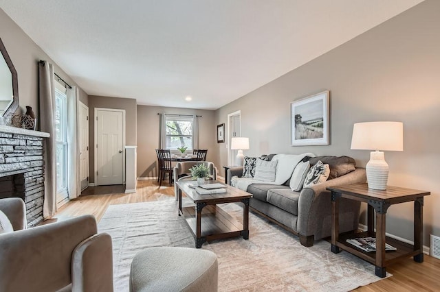 living room featuring light wood-style floors, baseboards, and a fireplace