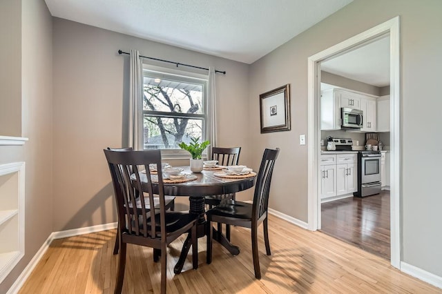 dining space featuring light wood-type flooring and baseboards