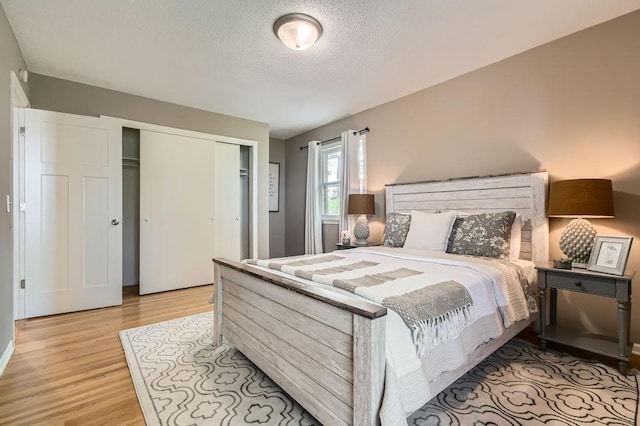 bedroom featuring light wood-style floors, a closet, and a textured ceiling