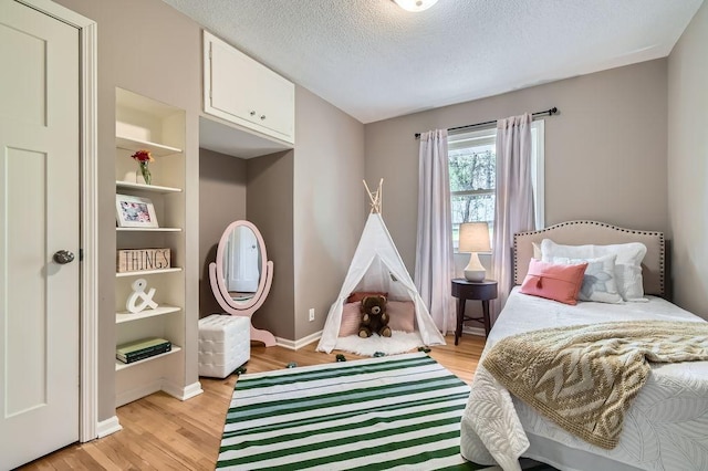 bedroom featuring light wood-style floors, a textured ceiling, and baseboards