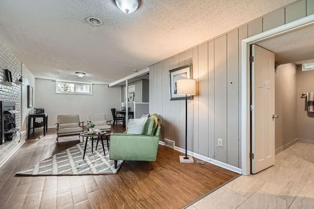 living area with a textured ceiling, baseboards, a fireplace, and wood finished floors