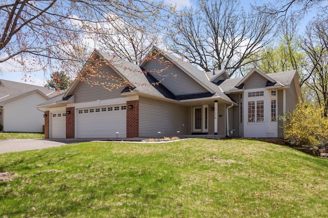 craftsman house featuring brick siding, an attached garage, a front lawn, and aphalt driveway