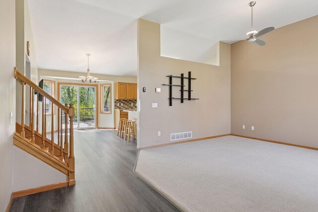 interior space featuring baseboards, ceiling fan with notable chandelier, wood finished floors, and visible vents