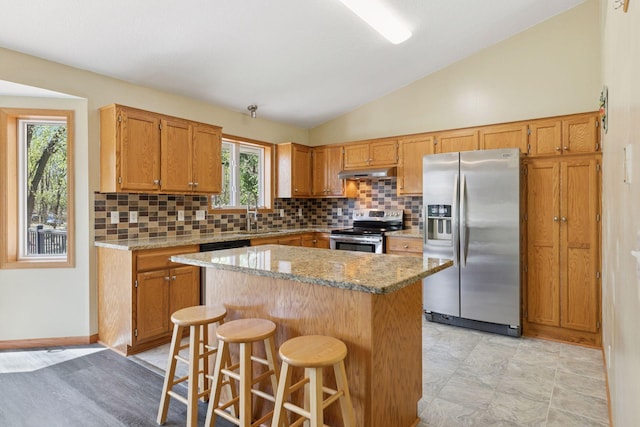 kitchen with decorative backsplash, stainless steel appliances, lofted ceiling, and under cabinet range hood