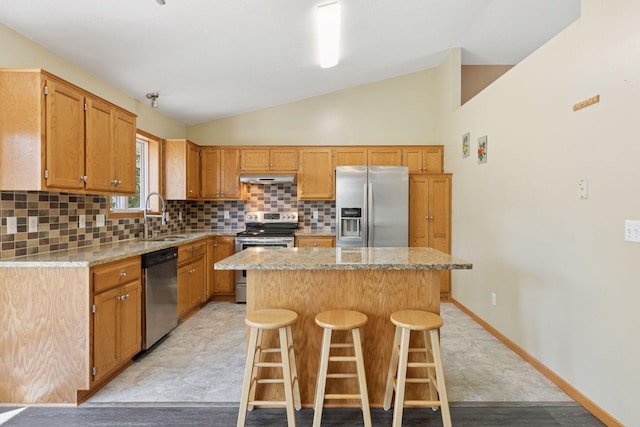 kitchen featuring a sink, a center island, stainless steel appliances, lofted ceiling, and tasteful backsplash