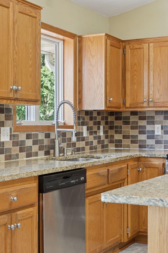 kitchen with a sink, tasteful backsplash, stainless steel dishwasher, and light stone countertops