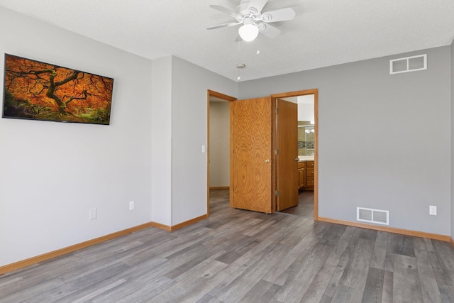 unfurnished bedroom with baseboards, wood finished floors, and visible vents