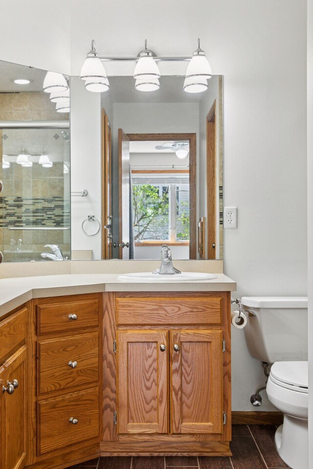 bathroom with vanity, baseboards, a stall shower, and toilet