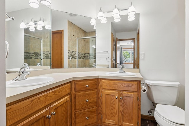 full bath featuring double vanity, toilet, a shower stall, and a sink