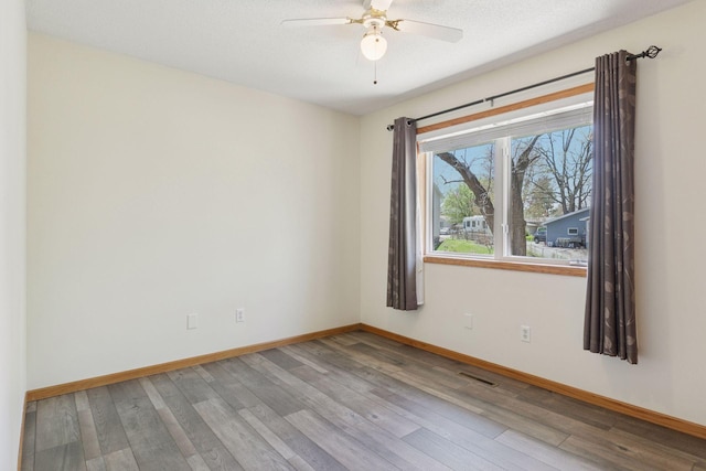 empty room with visible vents, baseboards, ceiling fan, and wood finished floors
