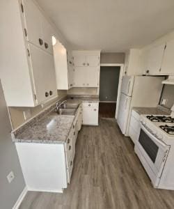 kitchen featuring white cabinetry, white gas range oven, a sink, and wood finished floors