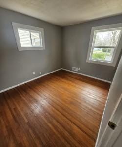 empty room with baseboards, dark wood-style floors, and plenty of natural light