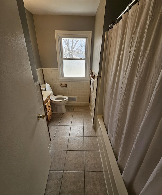 bathroom featuring tile walls, a wainscoted wall, vanity, toilet, and a shower with shower curtain