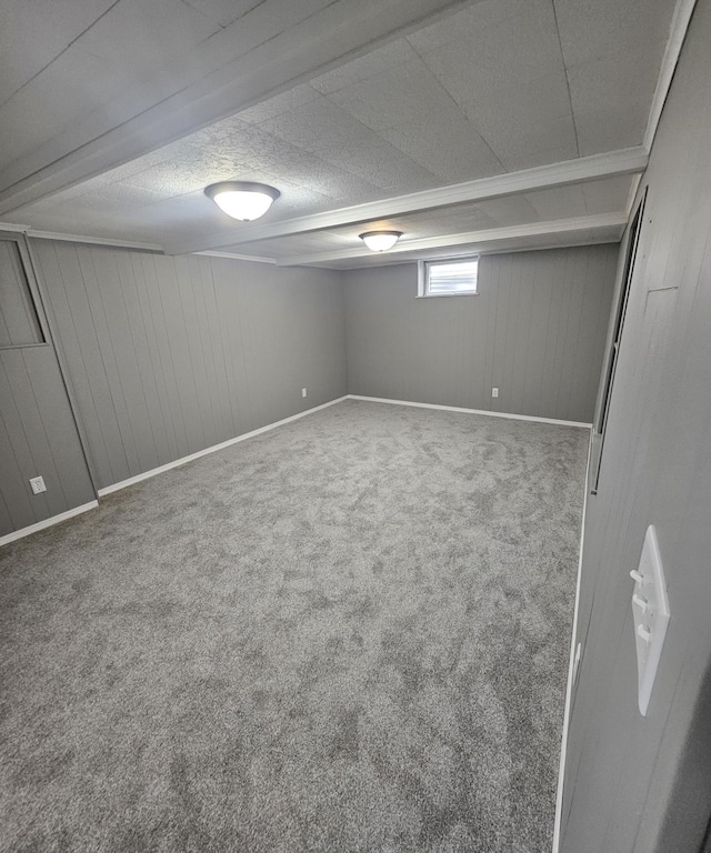below grade area featuring wooden walls, a textured ceiling, baseboards, and carpet