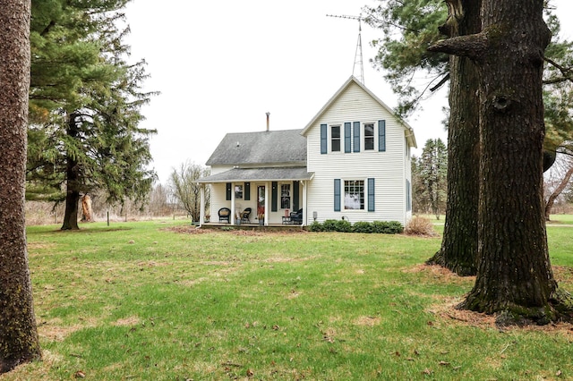 rear view of property featuring a lawn, covered porch, and roof with shingles