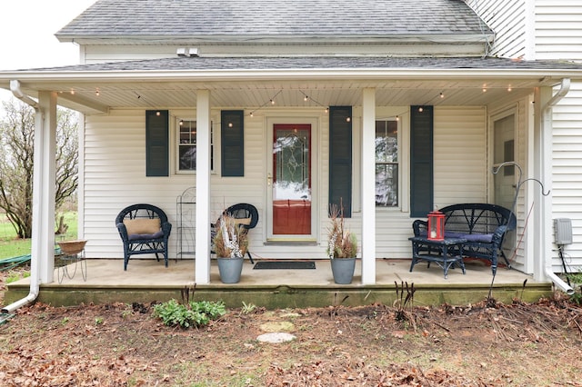 doorway to property with covered porch and roof with shingles