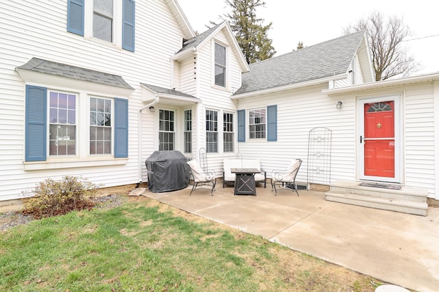 rear view of property featuring a lawn, a shingled roof, and a patio area