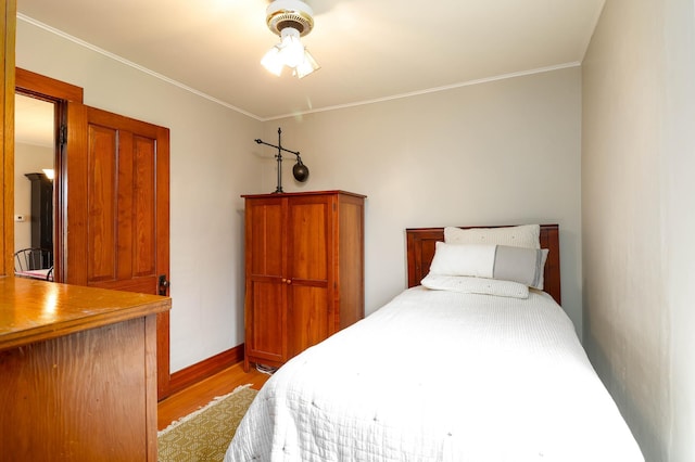 bedroom with crown molding, baseboards, and wood finished floors