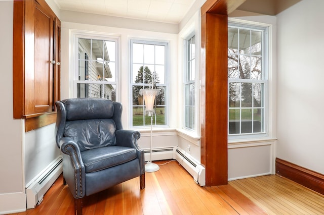 sitting room with baseboard heating, a wealth of natural light, and light wood finished floors