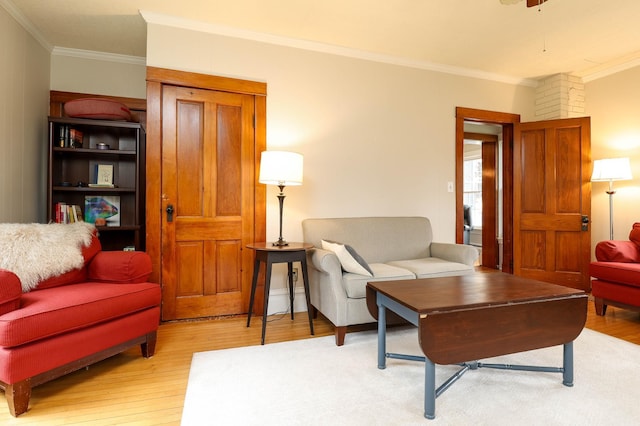 living area featuring crown molding, a ceiling fan, and light wood finished floors