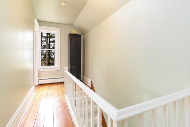 hallway with light wood finished floors, lofted ceiling, baseboard heating, and an upstairs landing