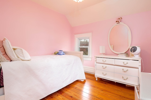 bedroom with baseboards, lofted ceiling, and light wood finished floors