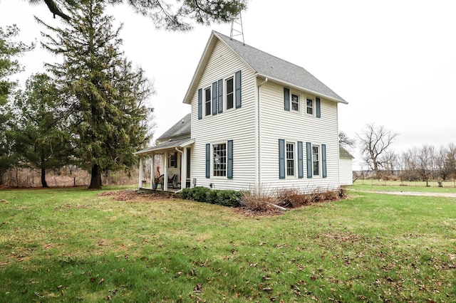 view of side of property with a shingled roof and a yard