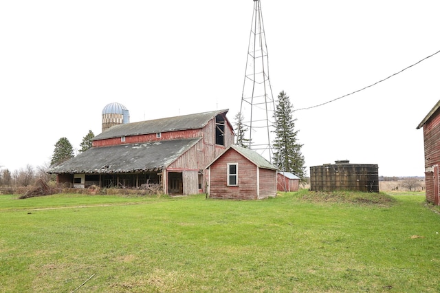 back of house featuring a barn, an outdoor structure, and a lawn