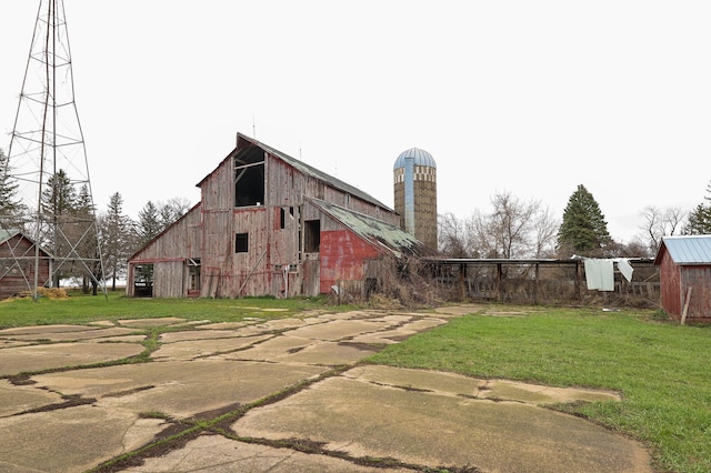 back of property featuring a barn, a lawn, and an outbuilding