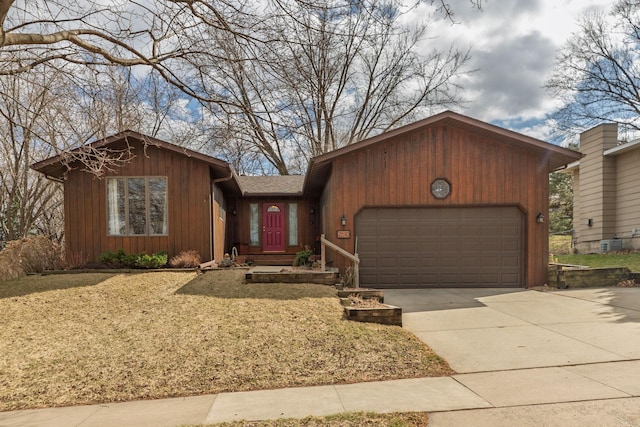 view of front facade with roof with shingles, an attached garage, concrete driveway, and a front lawn