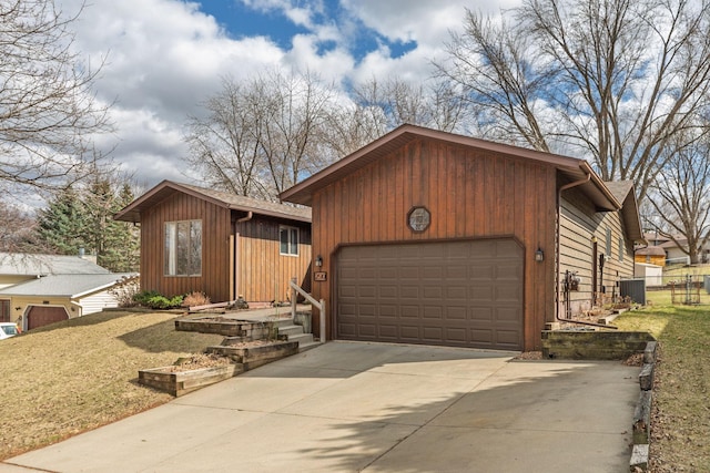 view of front of home featuring an attached garage, driveway, central AC unit, and a front lawn