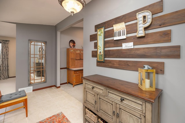 corridor featuring light tile patterned floors, baseboards, and visible vents