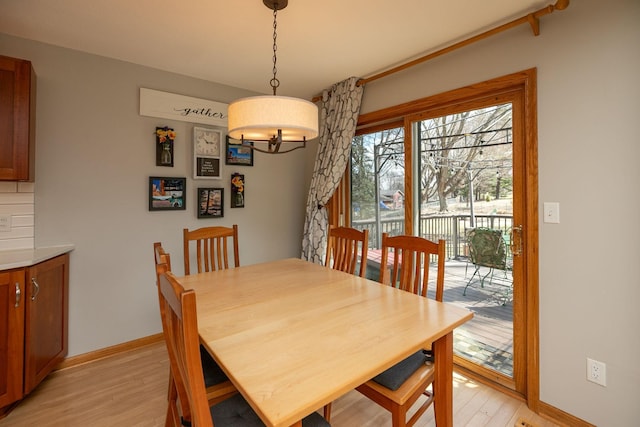 dining area featuring baseboards, an inviting chandelier, and light wood-style floors